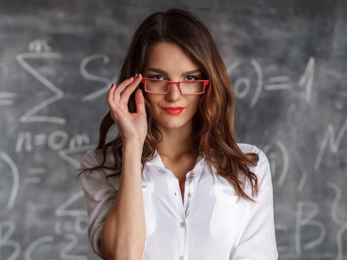 Attractive woman roleplaying a sexy teacher and standing in front of a chalk board